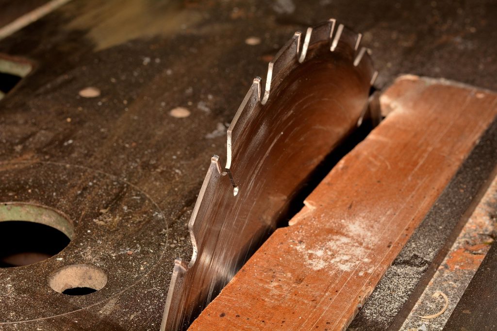 Older table saw setup with exposed blade and timber stop in workshop environment